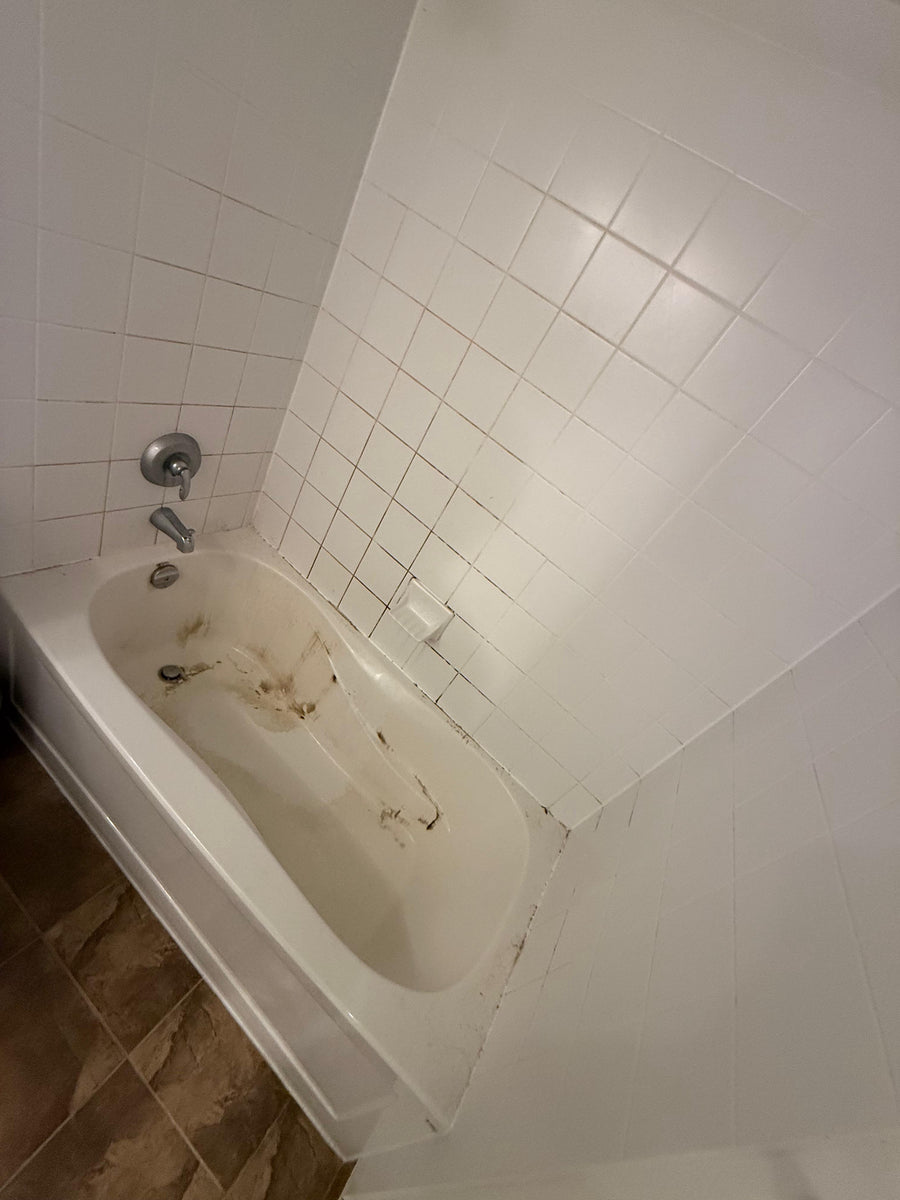 Dirty bathtub in a tiled bathroom corner