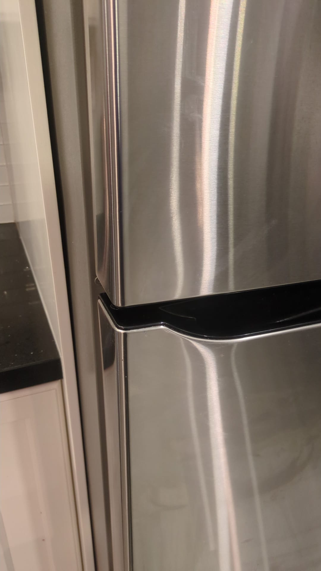 Cleaned Stainless steel refrigerator with a black handle in a kitchen setting